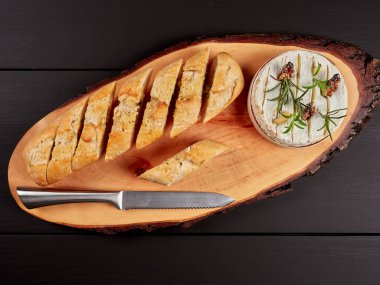 Cevizli kamembert peyniri, biberiye sapı ve sarımsaklı karanfil, kabuklu sarımsak gread ile servis ediliyor, kırsal bir tahtanın üzerinde, düz bir şekilde yatıyordu.
