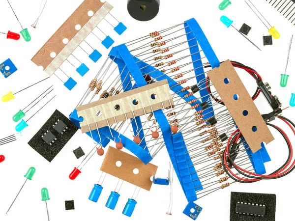 A selection of active and passive electronics components: buttons, LEDs, resistors, capacitors, buzzer, connecting wires, transistors and integrated circuit