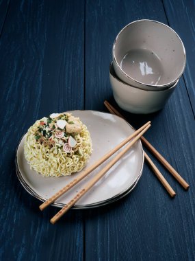 Tempura udong eriştesi malzemeleri, ahşap çubuklarla, koyu mavi arka planda.