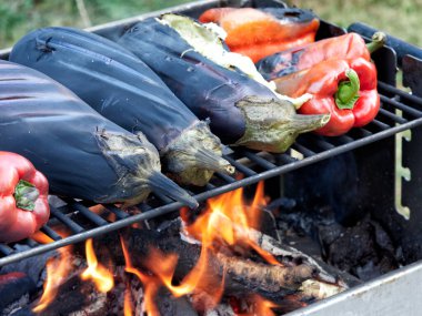 Patlıcanlar ve kırmızı biberler dışarıda rostoda pişiyor.