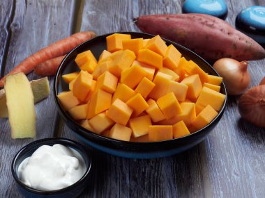 Gri kırsal arka planda tatlı patates ve zencefilli tereyağlı kabak çorbası.