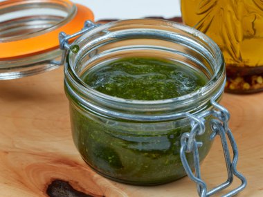 Tahtaya serpiştirilmiş taze naneli pesto kavanozu.
