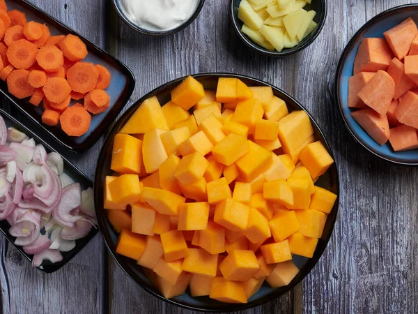 Gri kırsal arka planda tatlı patates ve zencefilli tereyağlı kabak çorbası.