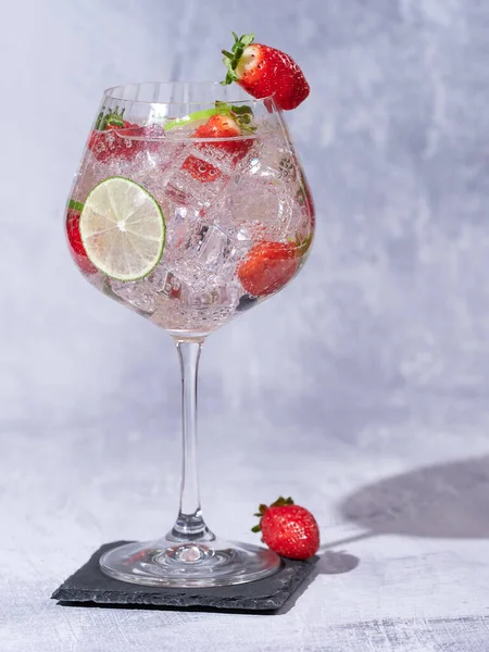 Strawberry gin decorated with a fresh strawberries and slices of lime