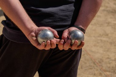 Hands holding two metal petanque balls clipart