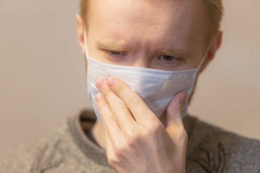 Coronavirus COVID-19 karantinası. Grip belirtileri gösteren maskeli genç bir adam. Yüksek vücut sıcaklığı.