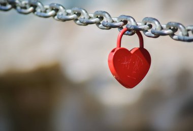 Red padlock in shape of heart hanging on a chain clipart