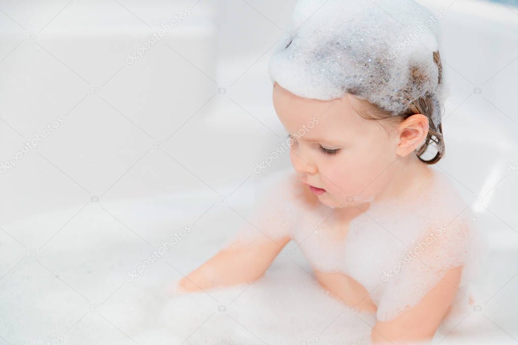 little girl have fun in the bath with soap on head