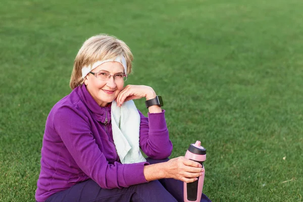 Idős nő pihen edzés után a parkban. — Stock Fotó