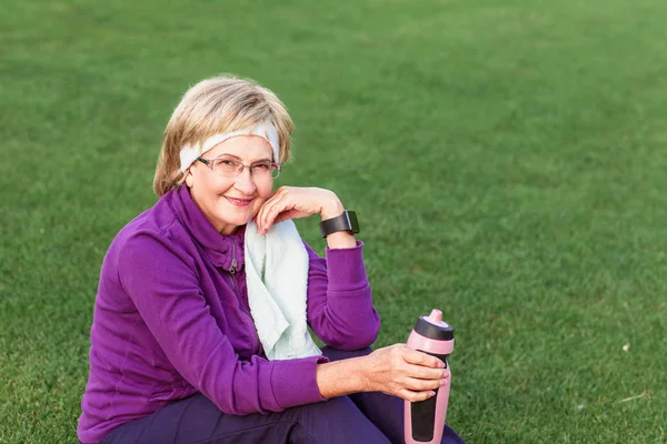 Volwassen vrouw rust na de training in het park Stockfoto