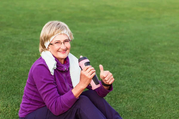 Volwassen vrouw rust na de training in het park Stockfoto