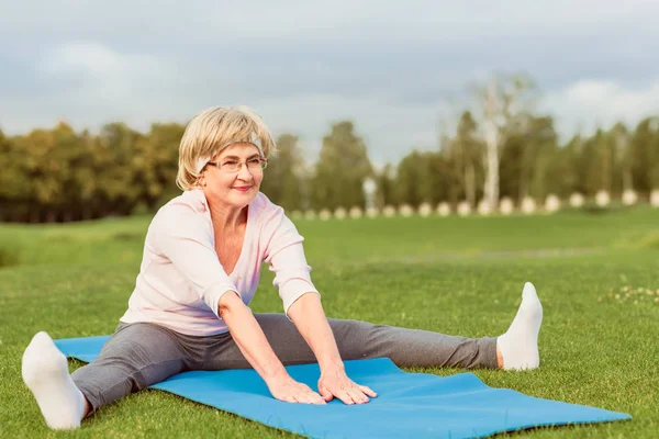Reife Frau praktiziert Yoga im Park lizenzfreie Stockfotos