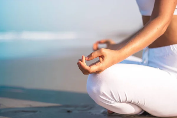 Een mooi meisje in witte kleren zit op de oceaan en het beoefenen van yoga en meditatie — Stockfoto
