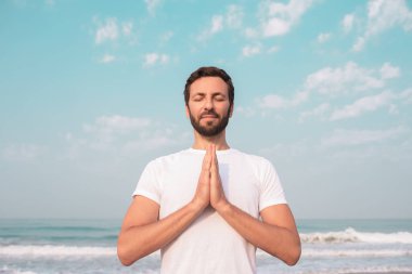 Mutlu adam sahilde oturur ve meditasyon yapar..