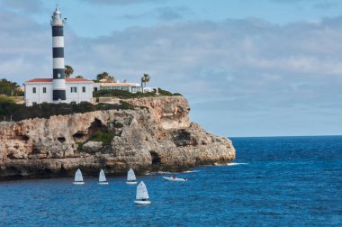 kayalar ve Porto Colom deniz feneri, Avrupa, İspanya, Balearic Adaları, Mallorca. Porto Colom. Rıhtım boyunca yürüyün. deniz feneri.