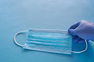 Mavi tıbbi maske bulaşıcı hastalıklardan korunmak için mavi arka plandaki tıbbi maskede bulunan bulaşıcı hastalıklardan korunmak için. Hava kirliliği, zatürree salgınları, koronavirüs salgınları ve biyolojik kirlenme riski.