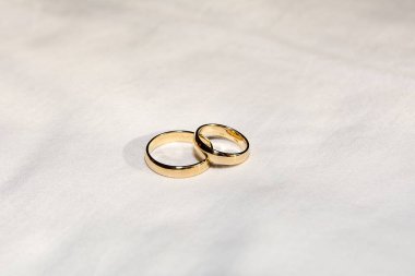 Two golden wedding rings on the white fabric