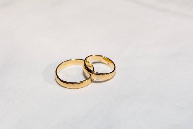 Two golden wedding rings on the white fabric