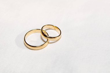 Two golden wedding rings on the white fabric