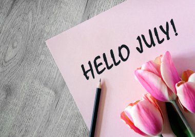 Merhaba, pembe bir çarşafta, siyah bir kalem ve bir buket lale ile Temmuz metni.