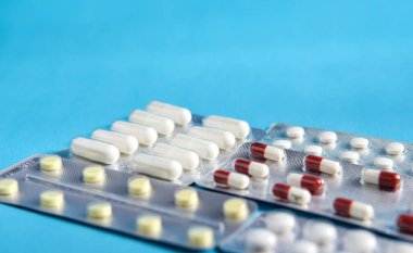 Mavi arka planda beyaz kırmızı sarı haplar olan bir su toplayıcısı. Virüslerden ve bakterilerden korunma. Antibiyotik, aşı..