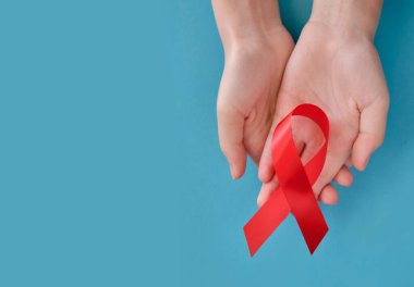 Kırmızı sembolik kurdele. AIDS, vaskülit, anoreksi, uyuşturucu bağımlılığı sorunu. Mavi arka planda çapraz iki el.