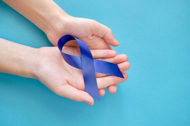 Blue ribbon on on two hands is a symbol of the problem of Stevens-Jones syndrome, colon cancer, problem of hydranencephaly, chronic fatigue syndrome, myalgic encephalomyelitis clipart