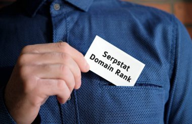 Tişörtlü bir adamın elinde beyaz bir tabela üzerinde alan adı metni