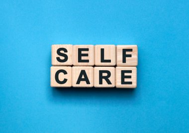SELF CARE - mavi arkaplandaki tahta küplerle ilgili metin
