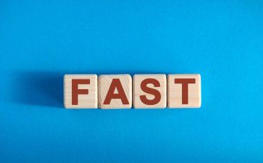 Tahta bloklar üzerine FAST metni, finansal iş konsepti, mavi arkaplan