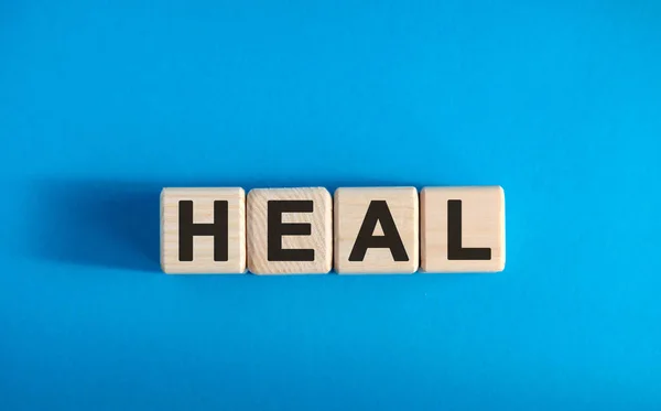 HEAL - ahşap bloklar üzerine metin, tıbbi konsept, mavi arkaplan