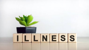 ILLNESS - beyaz arka planda tıbbi konsept. Tahta küpler ve saksıda çiçek.