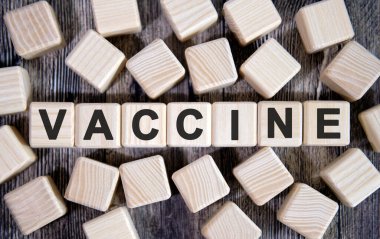VACCINE - medikal konsept, tahta küplerle ilgili yazı ve koyu arkaplanda bir sürü küp