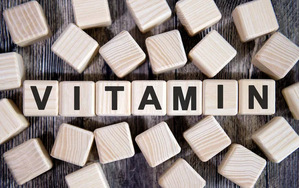 VITAMIN - Tıbbi konsept, tahta küplerle ilgili yazı ve koyu arkaplanda bir sürü küp