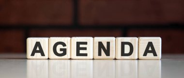 AGENDA - koyu tuğlalı arka planda iş dünyası finansal konsepti. Metinli tahta küpler