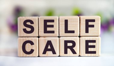 SELF CARE - Lale tomurcuklu çiçek arkaplanındaki tahta küplerle ilgili metin