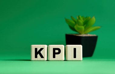 KPI - yeşil arka planda iş kavramı. Tahta küpler ve saksıda çiçek.