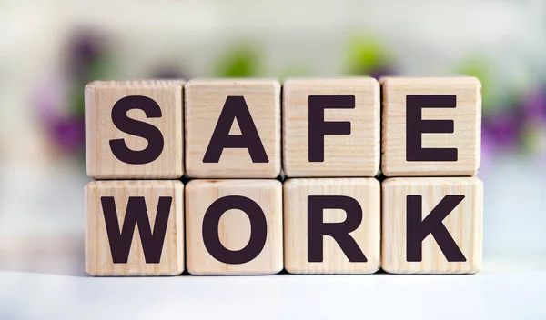 SAFE WORK - text on wooden cubes on a floral background with tulip buds