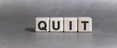 Tek renkli arkaplanda tahta küplerle ilgili QUIT metni