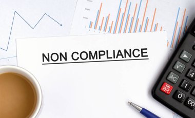 Grafikler, diyagramlar, hesap makinesi ve bir fincan mis kokulu kahve içeren NON COMPLIANCE belgesi