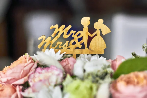 新娘和新郎的木制雕像在婚礼花朵的框架内 — 图库照片
