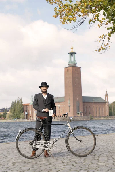 Hombre vistiendo traje negro a la antigua y sombrero sosteniendo una b vintage — Foto de Stock
