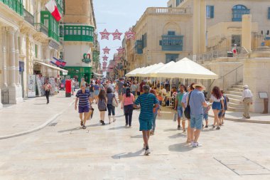 Valletta 'da eski taş sokaklarda yürüyen insanlar. Sıcak bir yaz. 