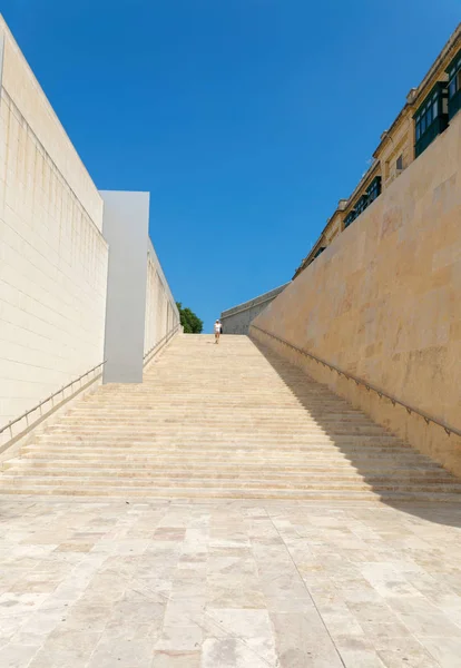 Ragazza che sale una lunghissima scalinata in pietra a La Valletta un caldo su — Foto Stock