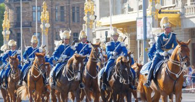 Kraliyet muhafızları mavi üniformalı, merkezde atın üstündeler.