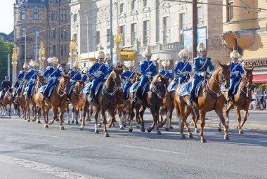 Kraliyet muhafızları mavi üniformalı, merkezde atın üstündeler.