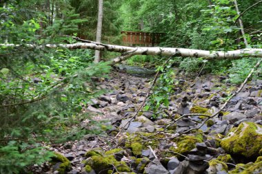 Rüzgâr kırması, altta kayalar ve uzaktan açılan bir köprü.