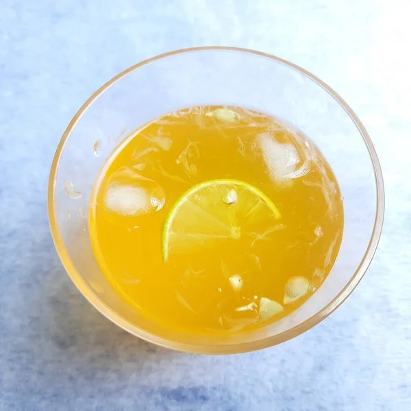 オレンジシロップとアイスキューブを追加したガラスのレモン汁と白の背景に美しく配置された内部レモンのスライス — ストック写真