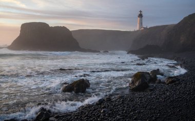 Newport, Oregon yakınlarındaki Cobble Sahili 'nden Yaquina Head Deniz Feneri' nin gün batımı manzarası