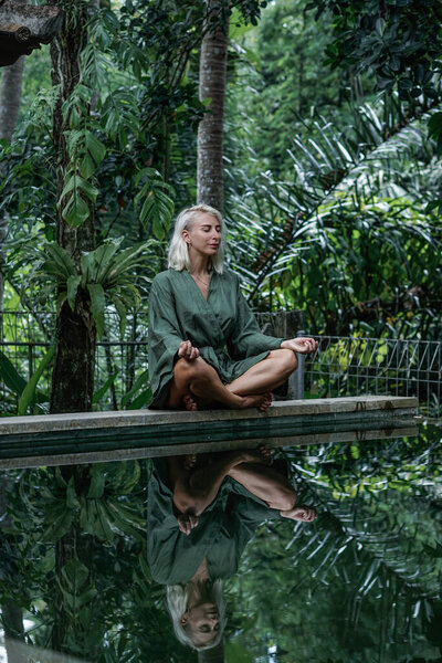 Young blonde woman in green kimono walking on jungle road